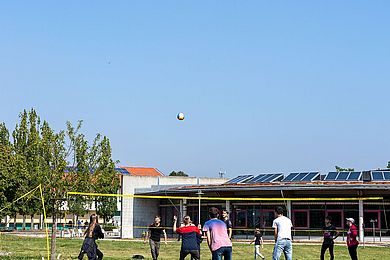 Teilnehmende spielen Volleyball auf der großen Wiese