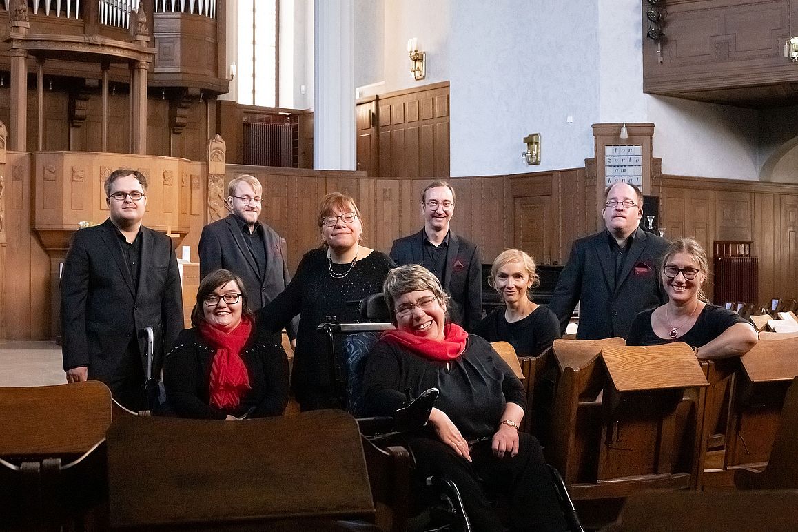 In einer Kirche wurde der inklusive Chor "Thonkunst" portraitiert. Die Mitglieder tragen schwarze Kleidung mit roten Accessoires.