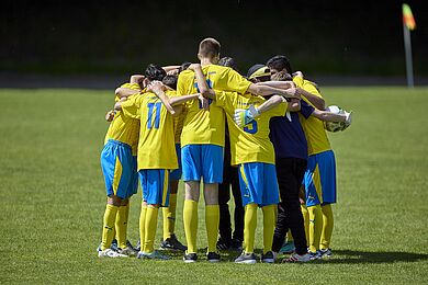 Mannschaft steht auf dem Feld im Kreis Arm in Arm
