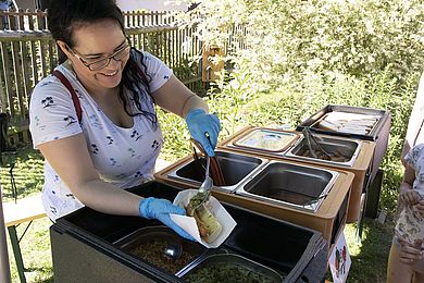 Eine Frau hilft beim Hot Dog Buffet