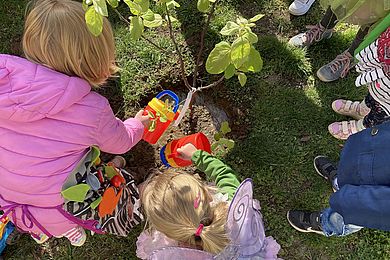 Zwei Kinder gießen das kleine Bäumchen.