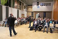 Eine Person spricht in ein Mikorfon vor einem großen, sitzendem Publikum auf der Inklusionskonferenz AuVschwung