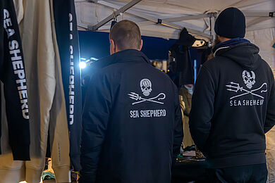 Zwei Personen von Sea Shepard mit schwarzen Jacken und weißer Aufschrift