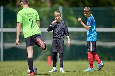 Spieler auf Fußballplatz, Schiedsrichter pfeift