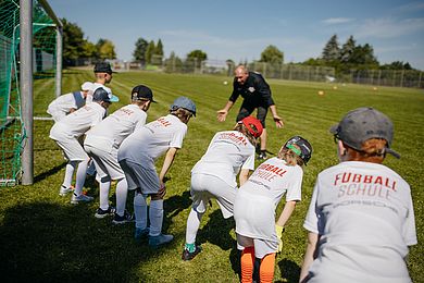 Ein Trainer erklärt Teilnehmenden der RB Fußballschule etwas