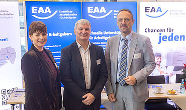v.l. Ira Kummrow (Abteilungsleiter*in Kompetenzzentrum für Vermittlung und Integration), Steffen Leonhardi (Vorsitzender der Geschäftsführung der Agentur für Arbeit Leipzig), Tobias Schmidt (Hauptgeschäftsführer*in BBW-Leipzig-Gruppe) vor dem Stand der EAA Sachsen