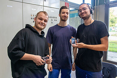 3 Auszubildende präsentieren die neue Technologie mit Kopfhörern und digitalen Geräten