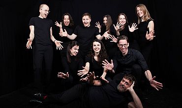 Theatergruppe mit ausgestreckten Händen fotografiert (9 Personen)