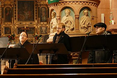 Mitglieder des inklusiven A-Capella-Ensembles Thonkunst tragen warme Kleidung und singen in einer Kirche.