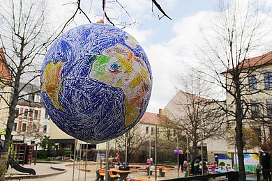 Eine gebastelte Weltkugel hängt am Baum