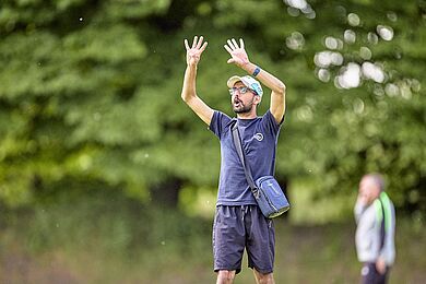 Person gibt Zeichen vom Spielfeldrand