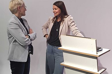 Studioszene beim AVWS-Fachtag. Am Stehpult unterhalten sich 2 Dozentinnen angeregt. 
