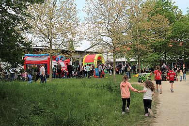 Besucher*innen beim Tag der offenen Tür - im Hintergrund sieht man Hüpfburgen