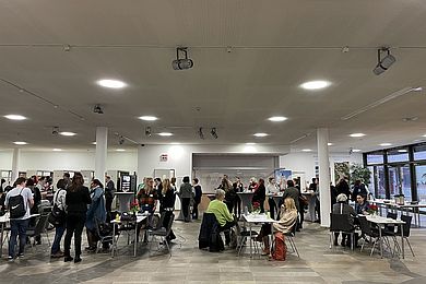 Im Foyer des Leipziger Kubus stehen und sitzen viele Menschen