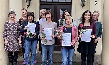 Die Mitarbeitenden der Kita "Am Schlosshof" halten Blumen und Zertifikate über das Weimarer Mentoring Programm in den Händen