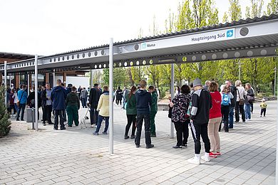 Eine Schlange an Menschen vor dem Haupteingang des Berufsbildungswerkes.